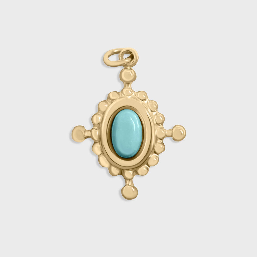 Gold compass pendant with a turquoise stone on a light gray background