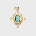 Gold compass pendant with a turquoise stone on a light gray background