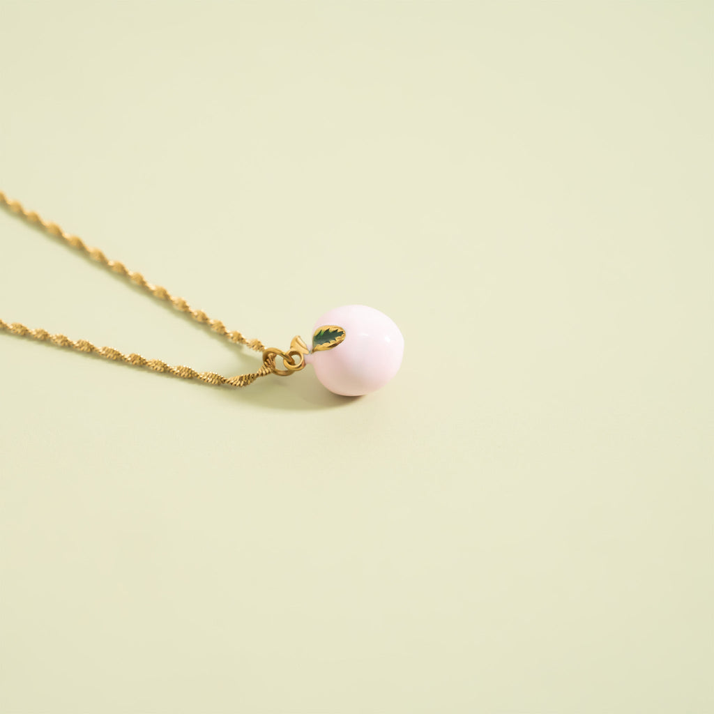 Necklace with a pink peach pendant on a light green background