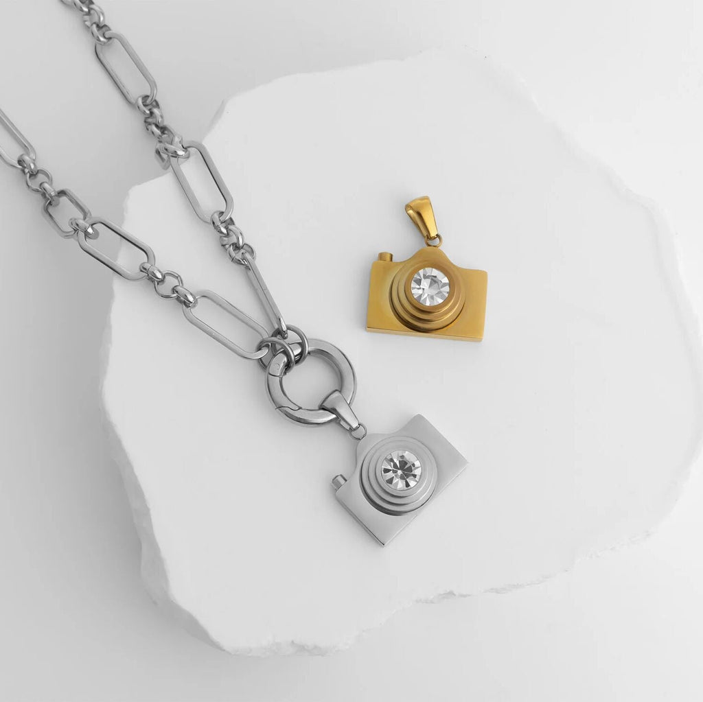 Silver and Gold camera-shaped pendant necklace on a white background