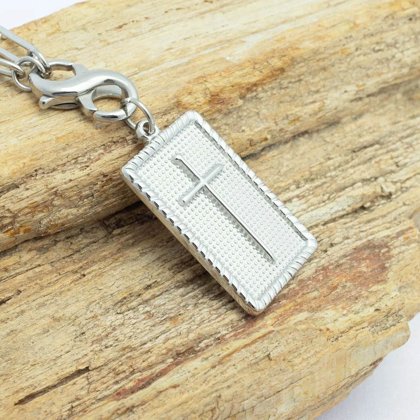 Silver cross pendant on a chain against a wooden background
