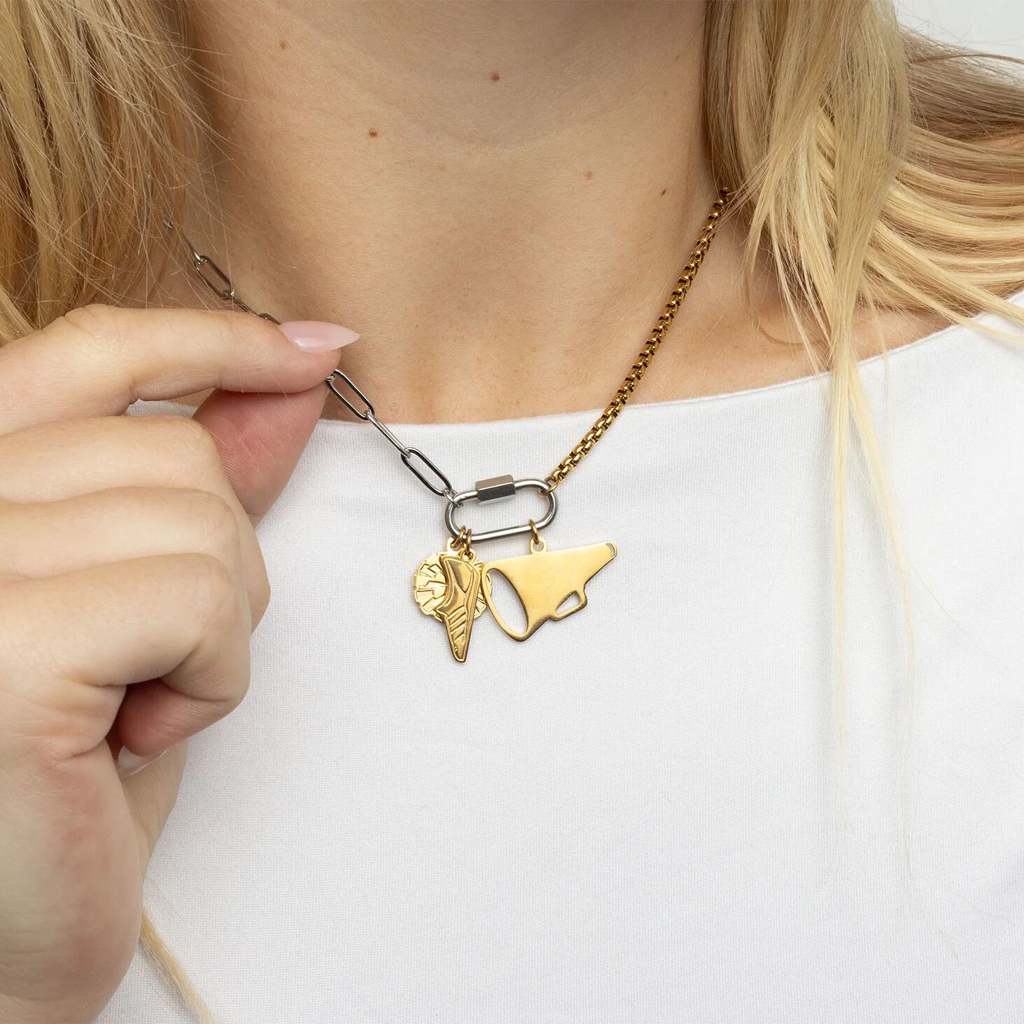 Gold necklace with unique pendant design worn by a person against a white background