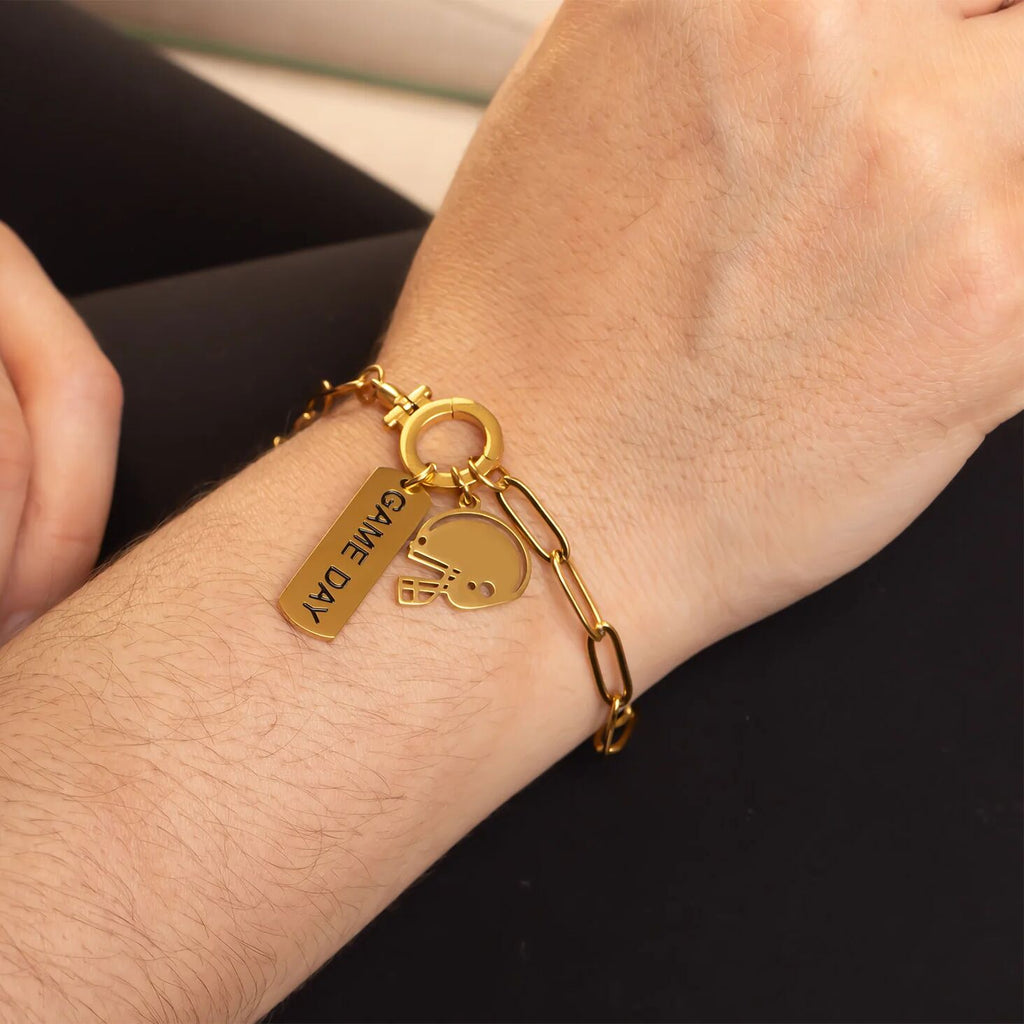 Gold bracelet with charms on a wrist against a black background