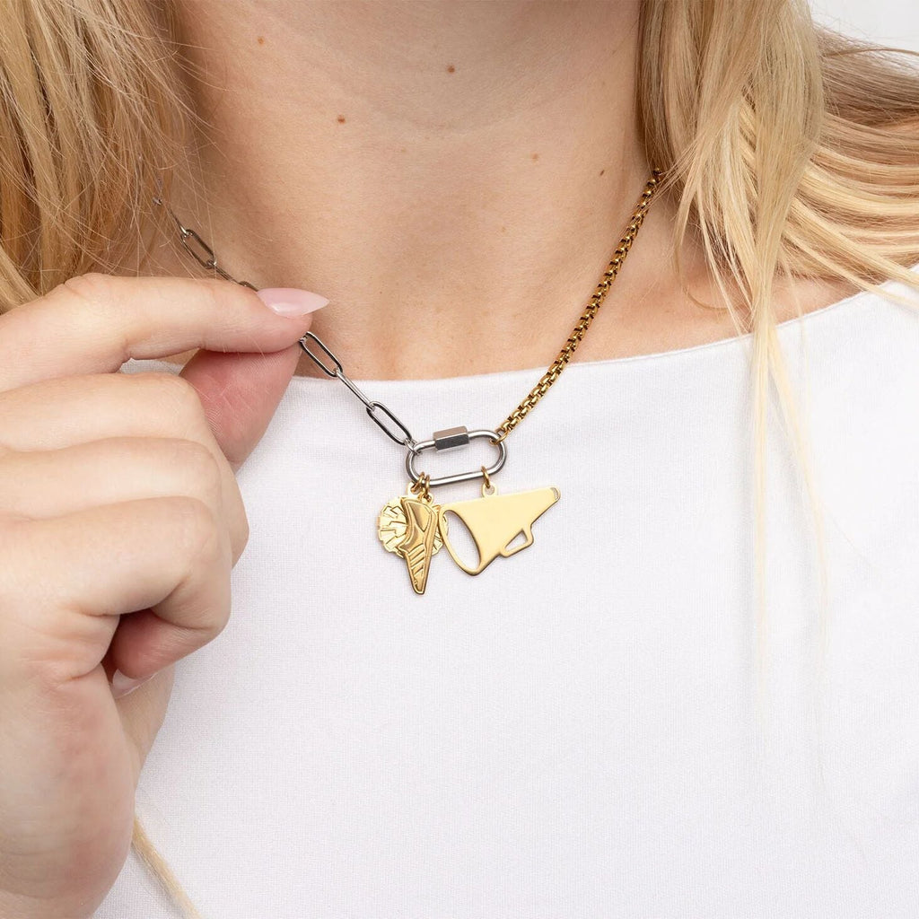 Gold necklace with two charms being adjusted by a hand on a white background