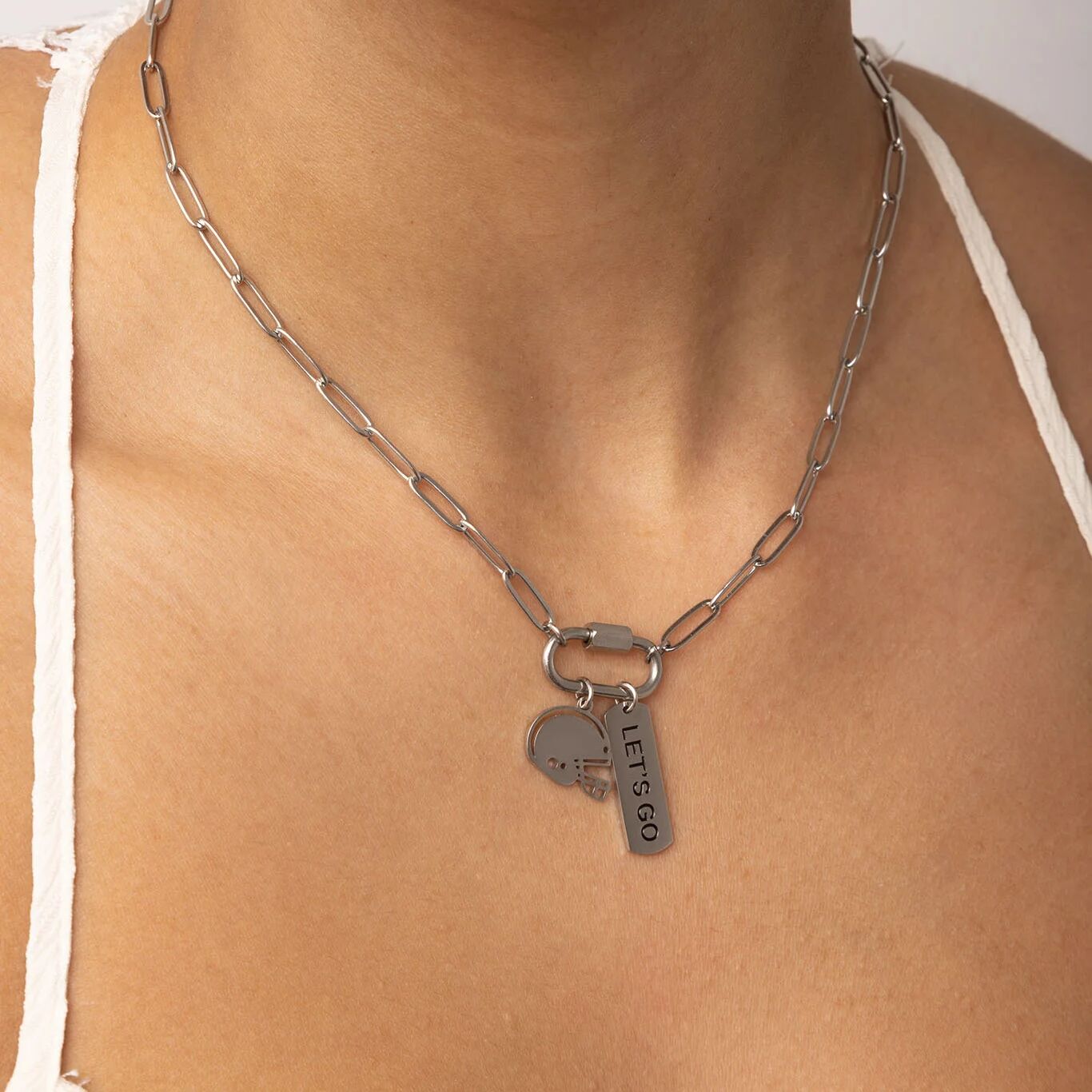 Silver chain necklace with a pendant on a person wearing a white top.
