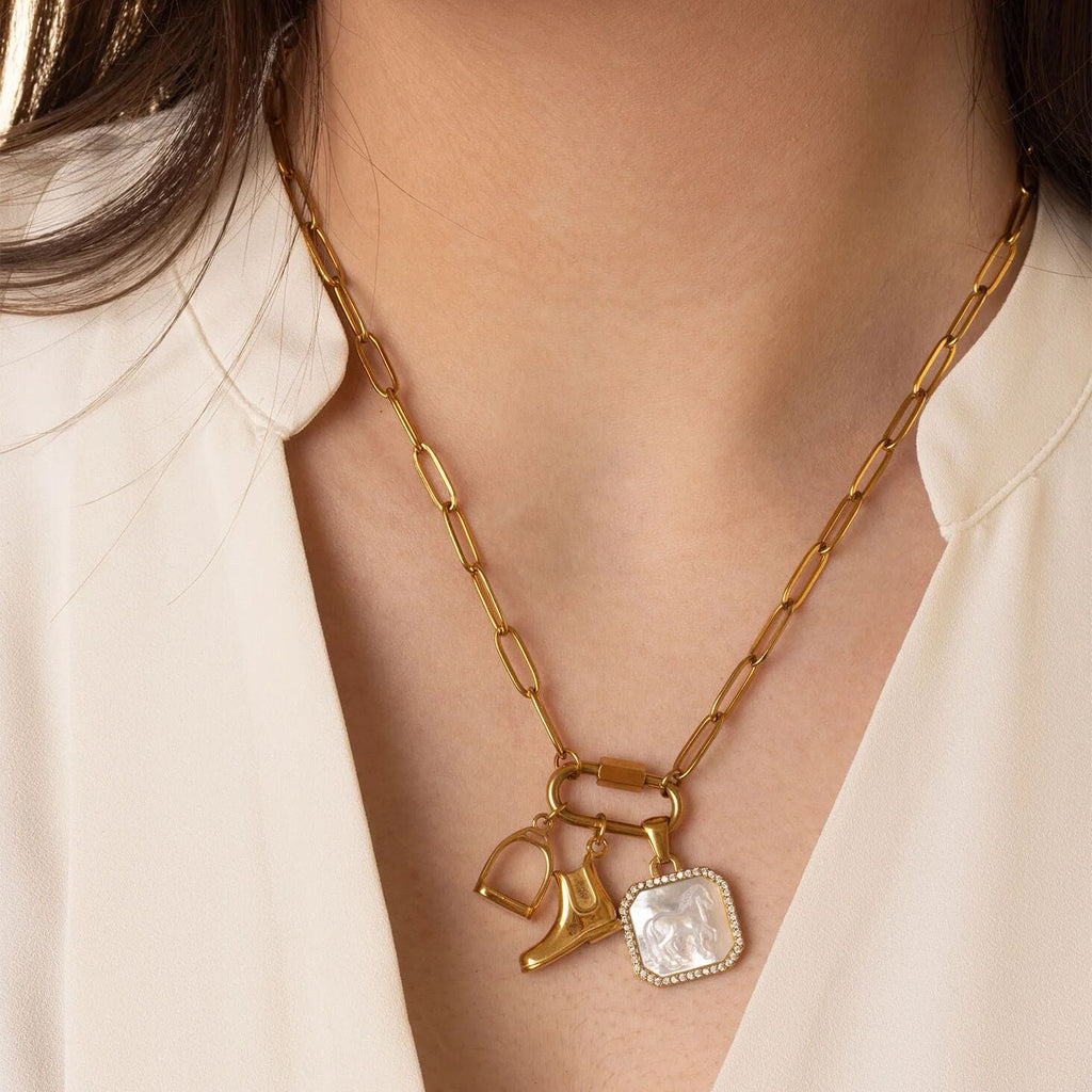 Gold necklace with equestrian charms on a person wearing a white blouse
