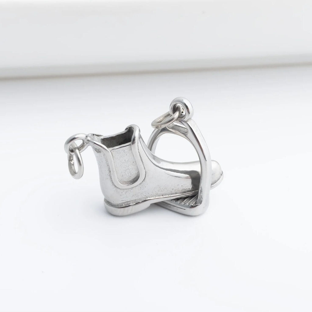 Silver equestrian boot and stirrup charm on a white background