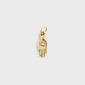 Gold charm shaped like a hand with an eye design on a light gray background
