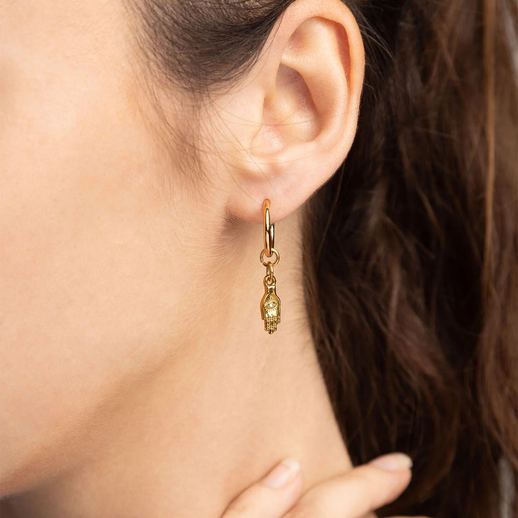 Gold earring with a green gemstone worn by a person