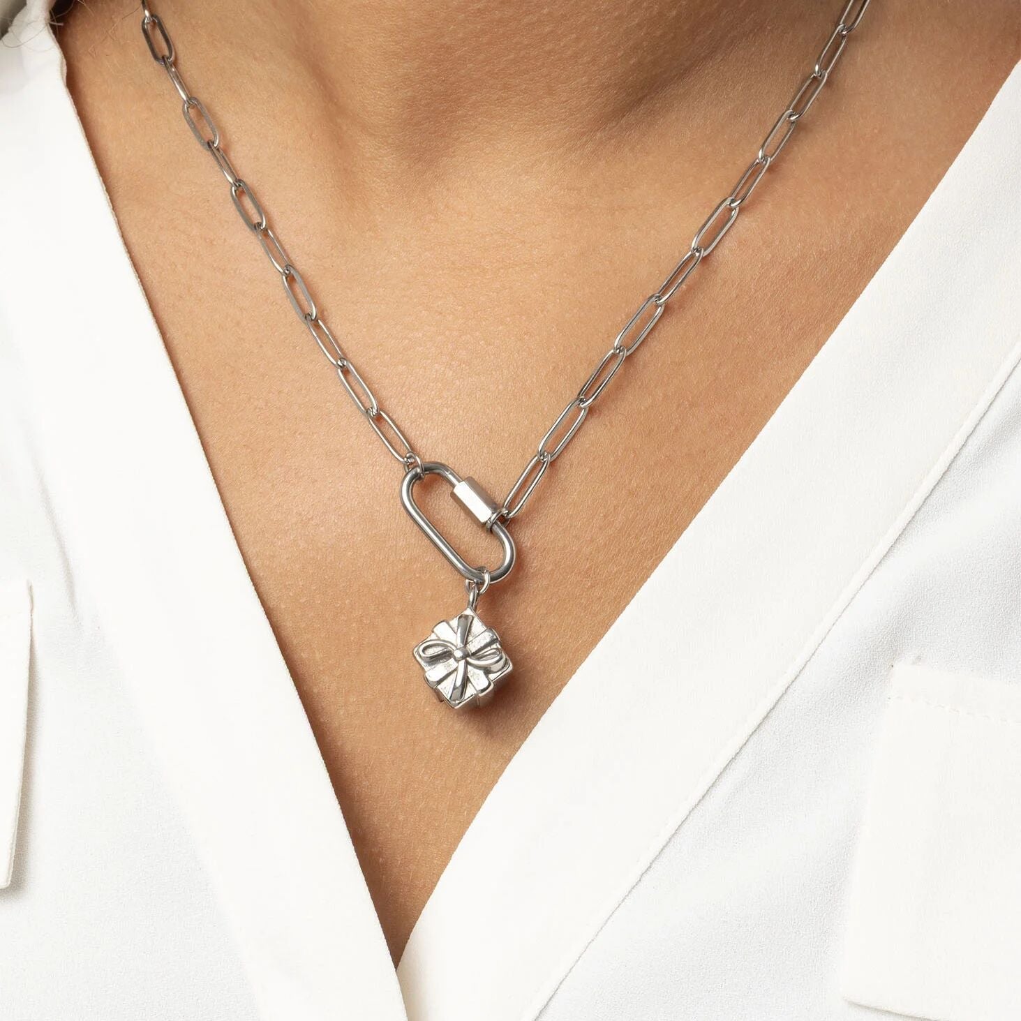 Silver necklace with a Present Charm worn by a person in a white outfit.