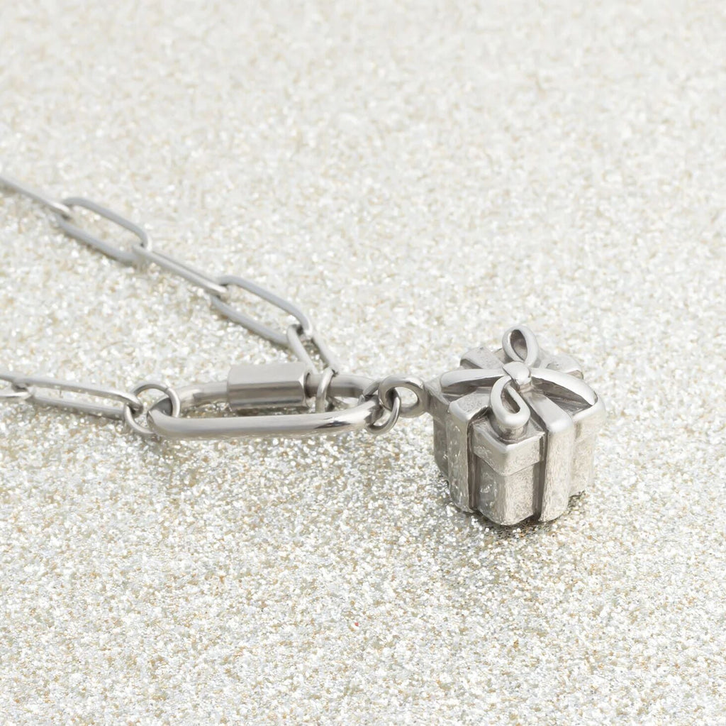 Silver necklace with a Present Charm on a textured white background