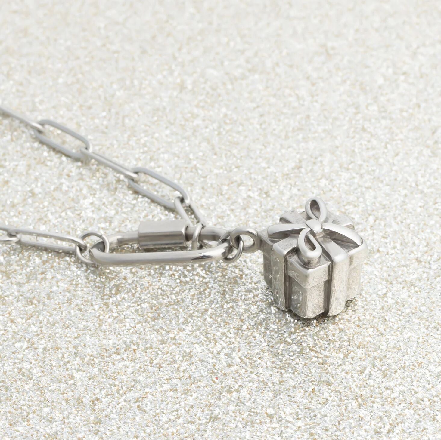 Silver necklace with a Present Charm on a textured white background