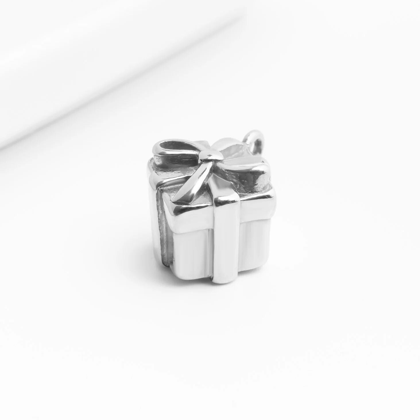 Silver gift box charm with a bow on a white background