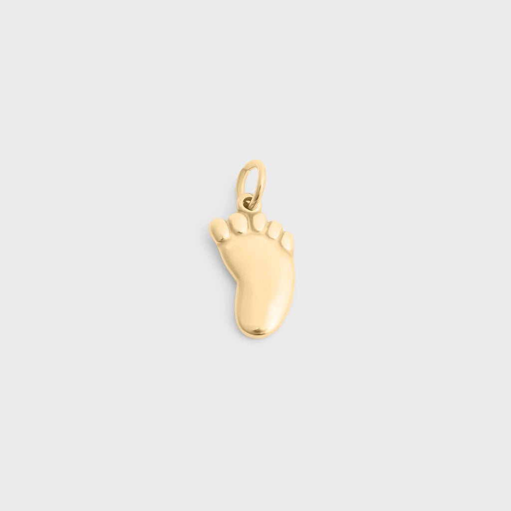 Gold baby foot-shaped charm on a light gray background