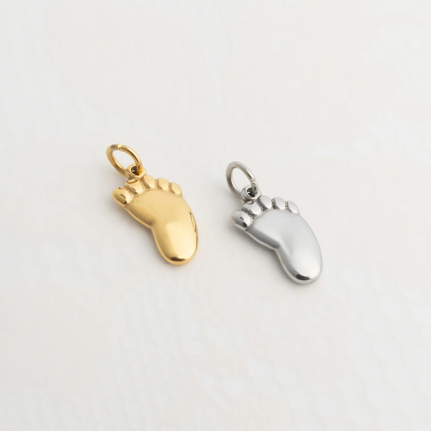 Gold and silver foot charm on a light gray background