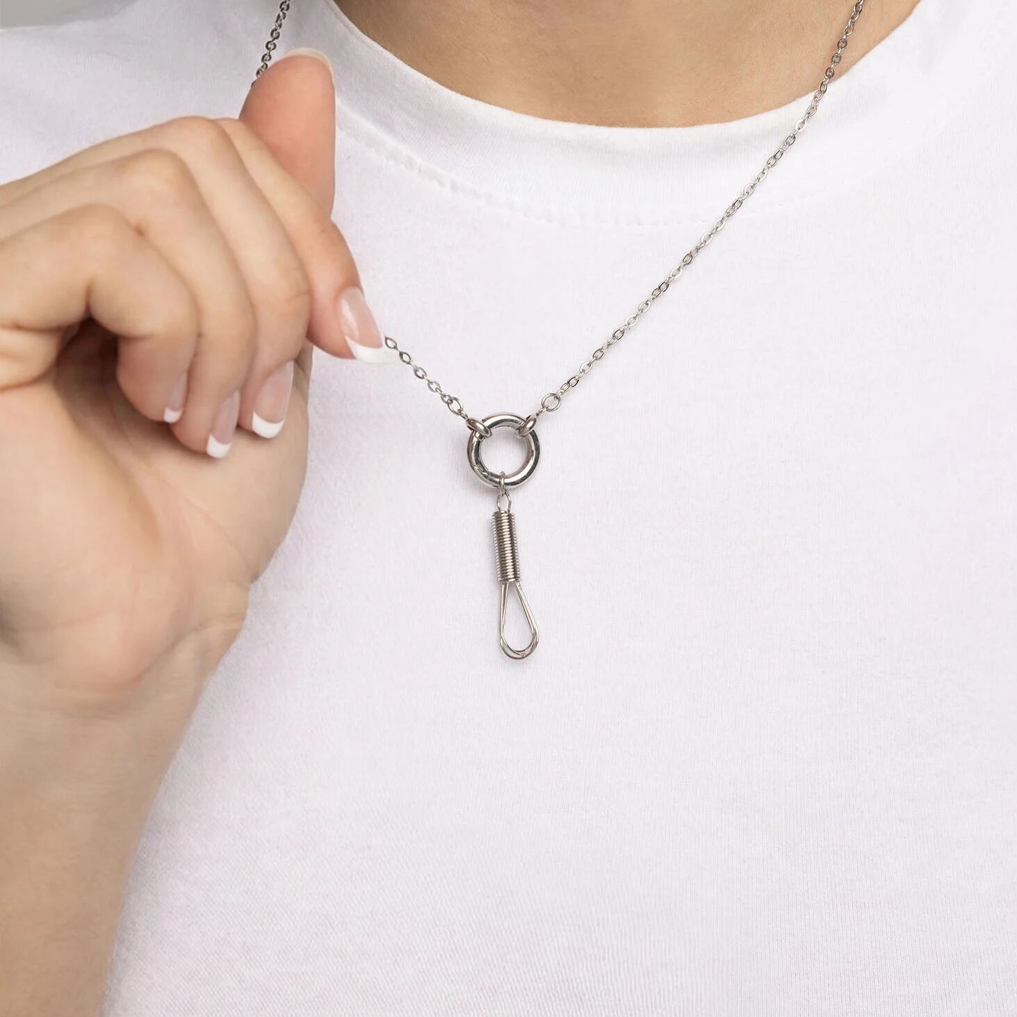 Silver necklace with a unique pendant held by a hand against a white background