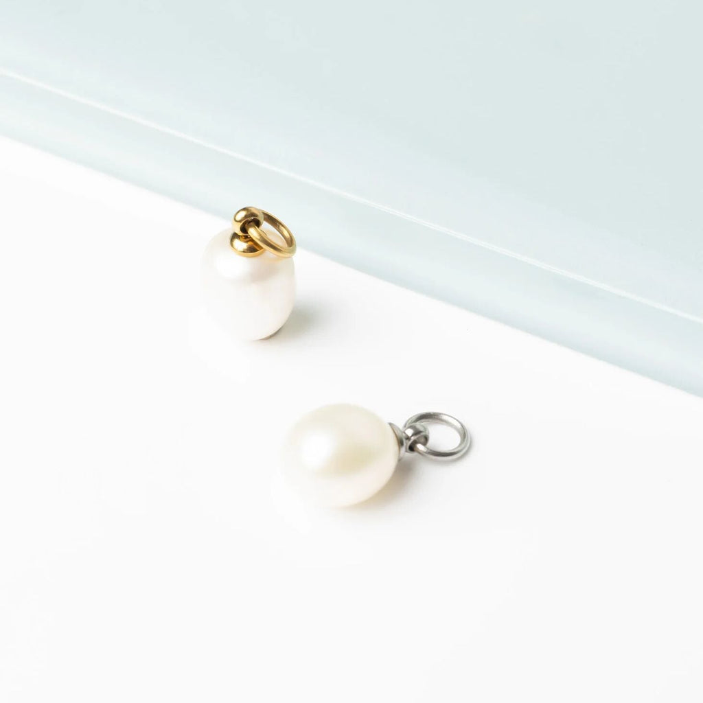 Pearl charms with gold and silver jump rings on a white background