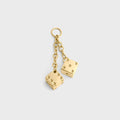 Gold dice-shaped earrings on a light gray background