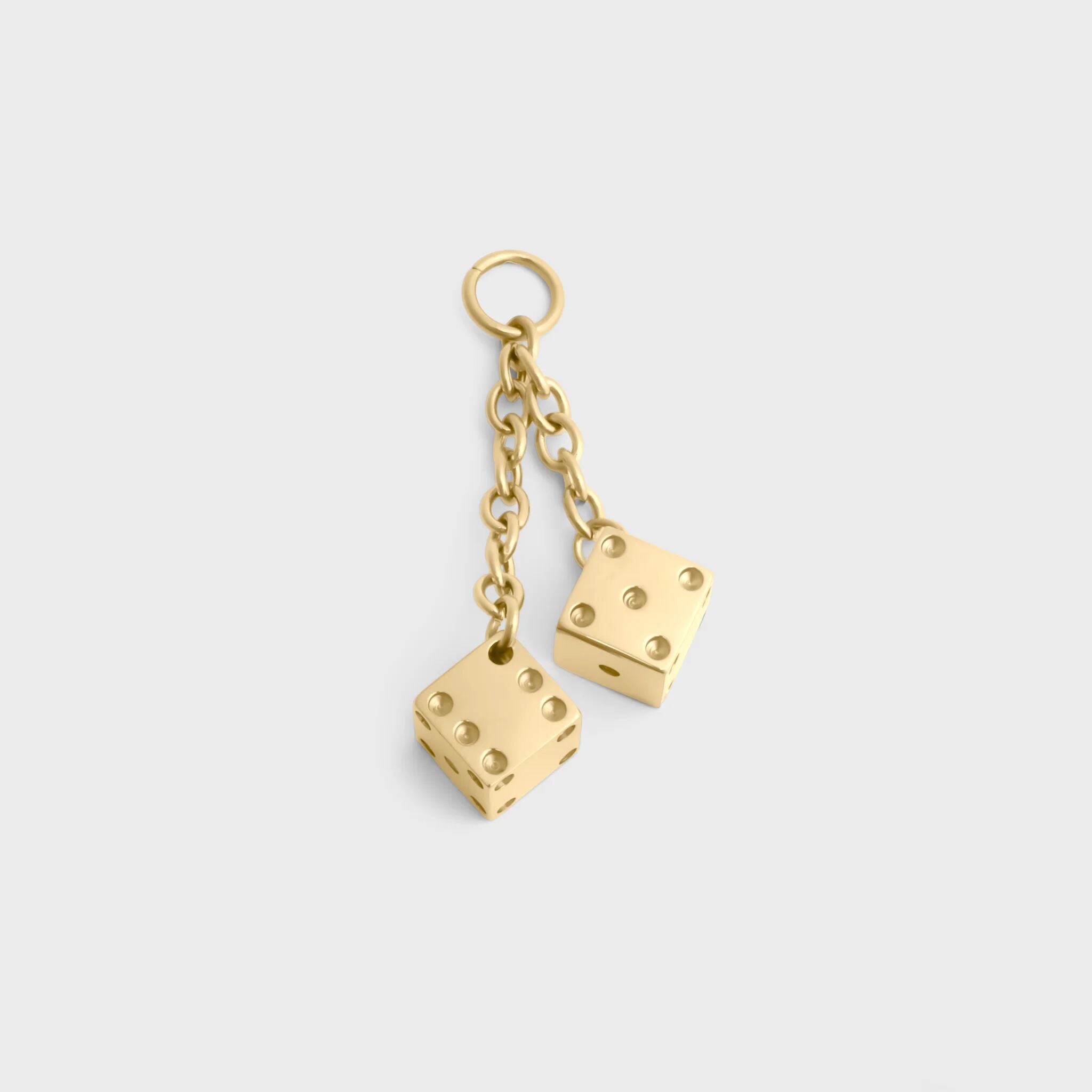 Gold dice-shaped earrings on a light gray background