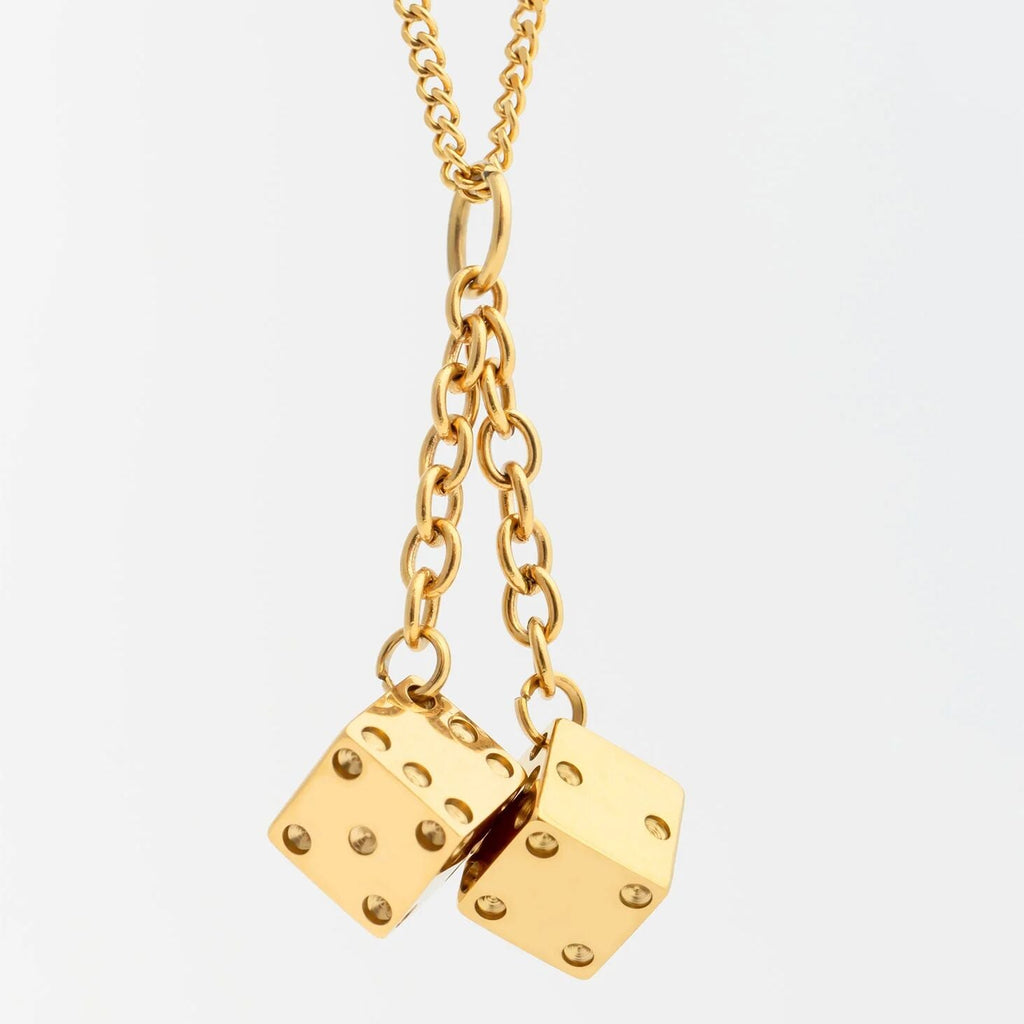 Gold necklace with dice pendants on a light gray background