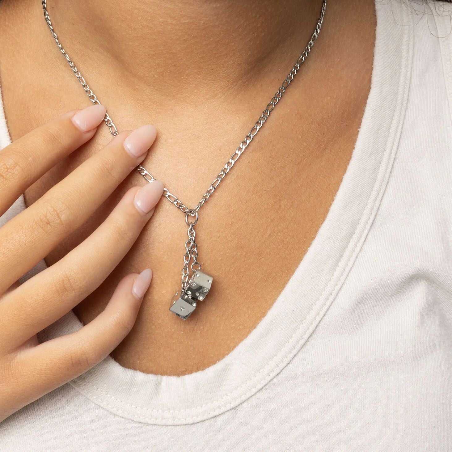 Silver necklace with a dice pendant worn by a person wearing a white shirt