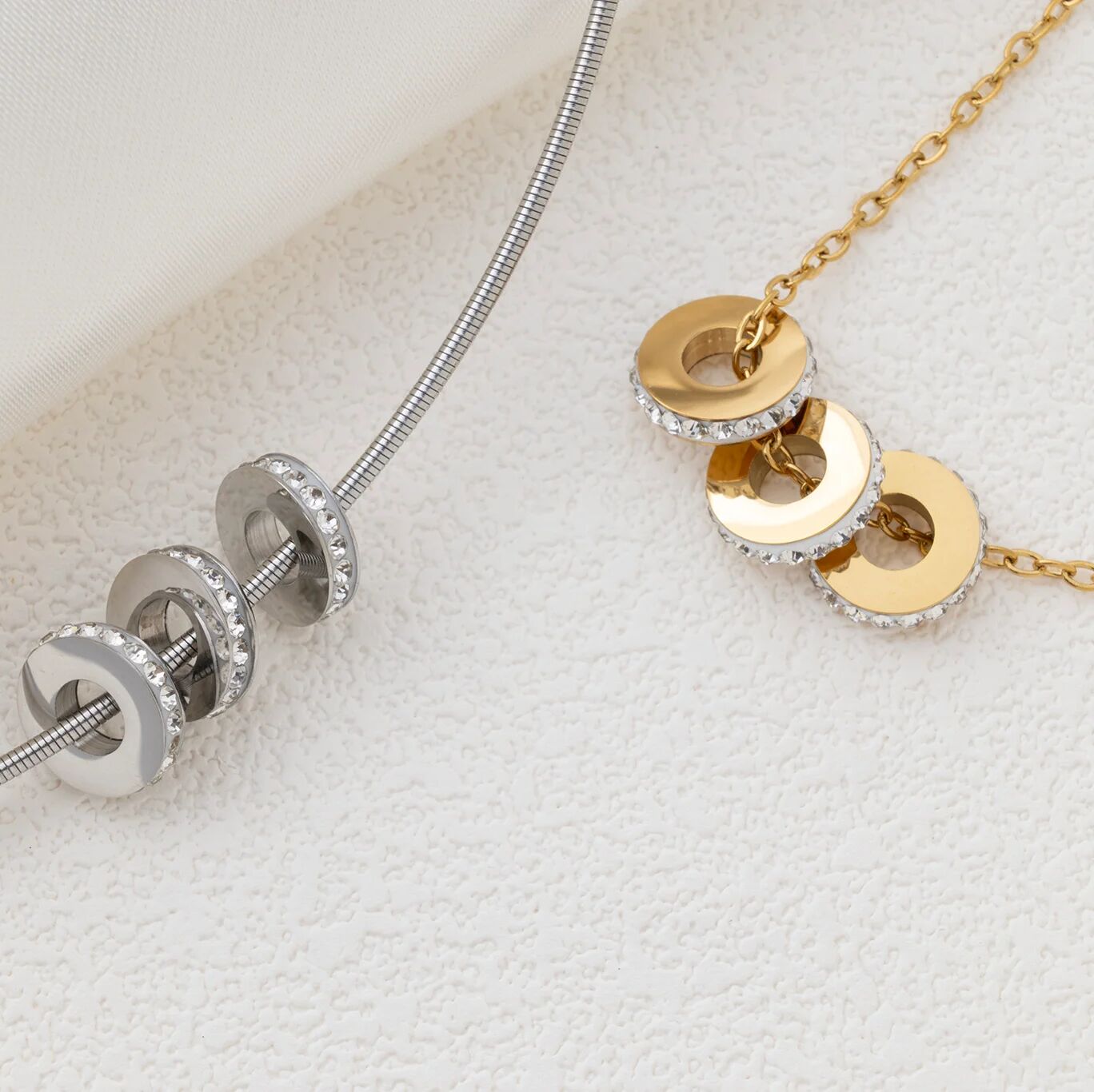 Gold and silver necklaces with spacer beads on a textured white surface
