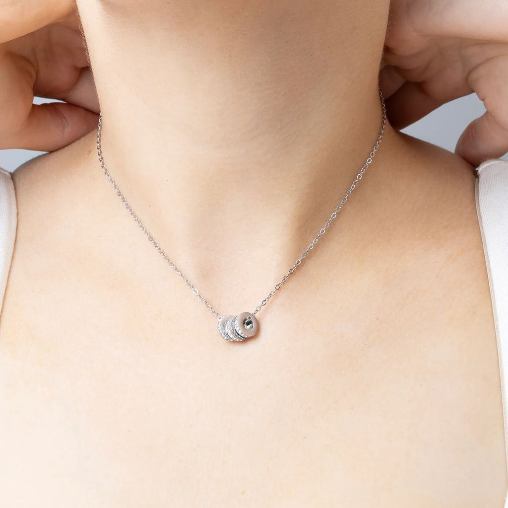 Silver necklace with spacer beads on a person's neck against a neutral background