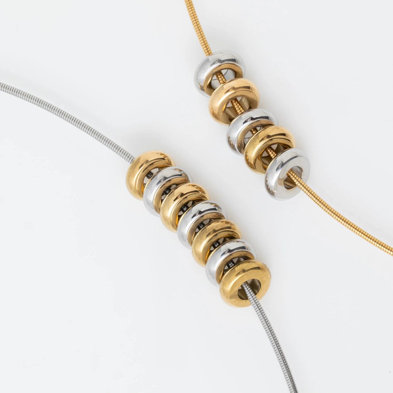 Close-up of gold and silver spacer beads on a necklace on a white background