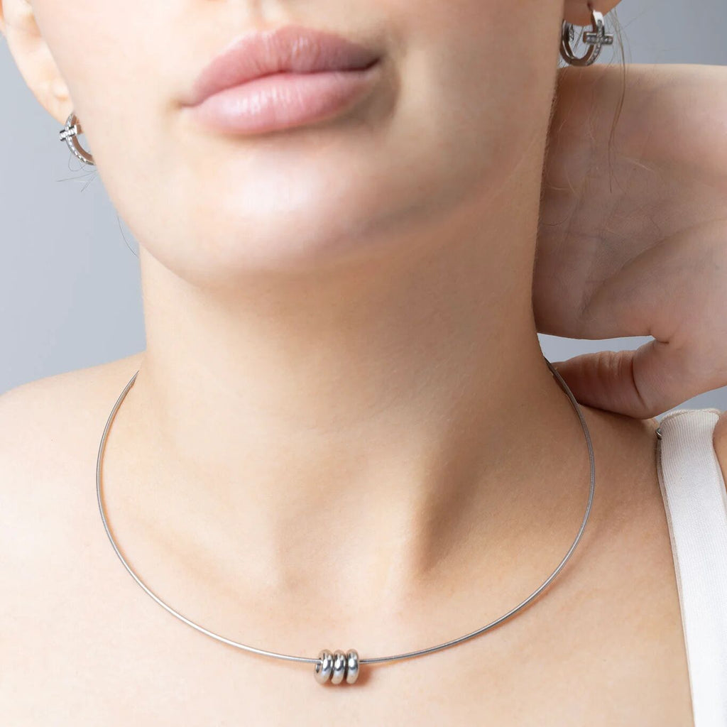 Close-up of a person wearing a silver necklace with a gray background