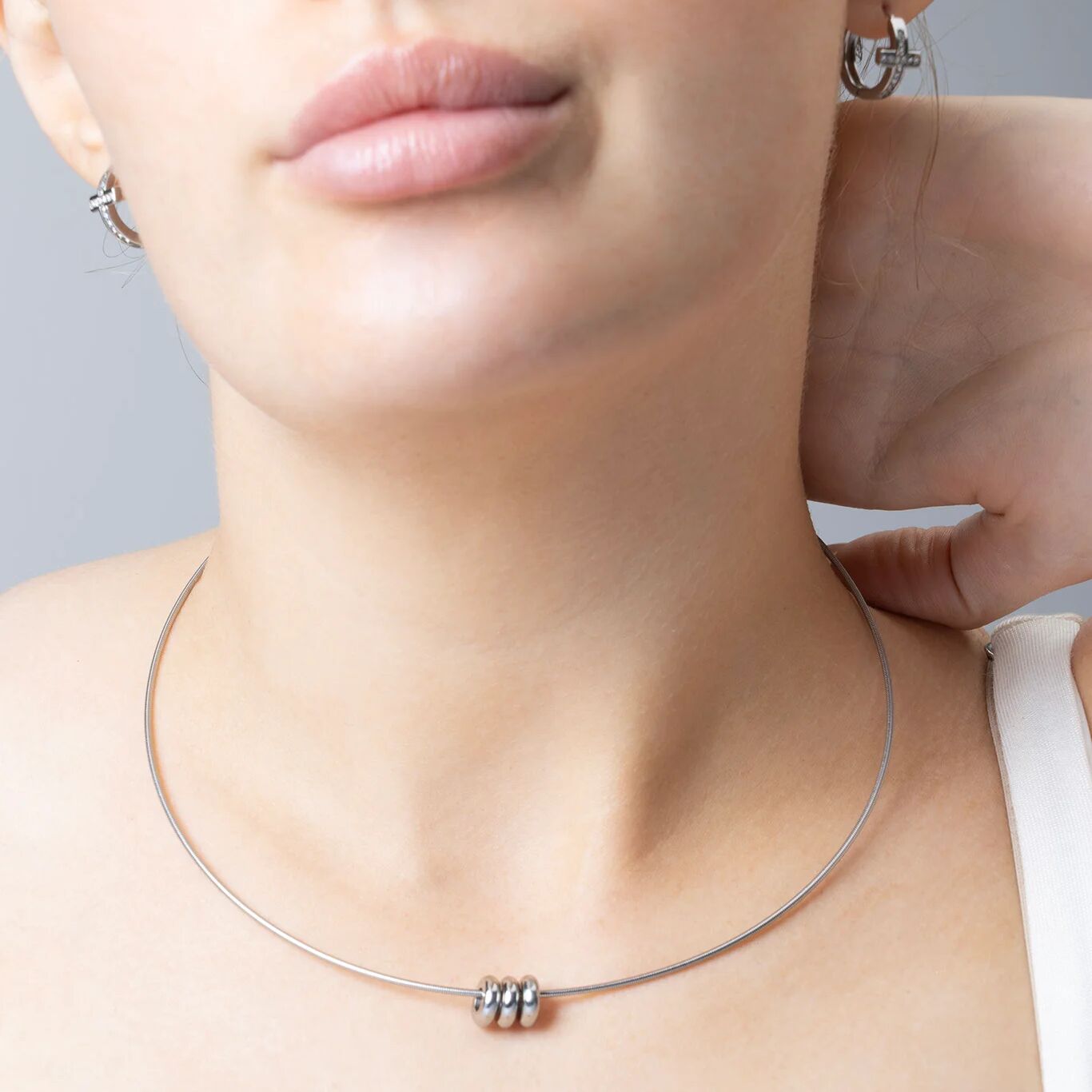 Close-up of a person wearing a silver necklace with a gray background