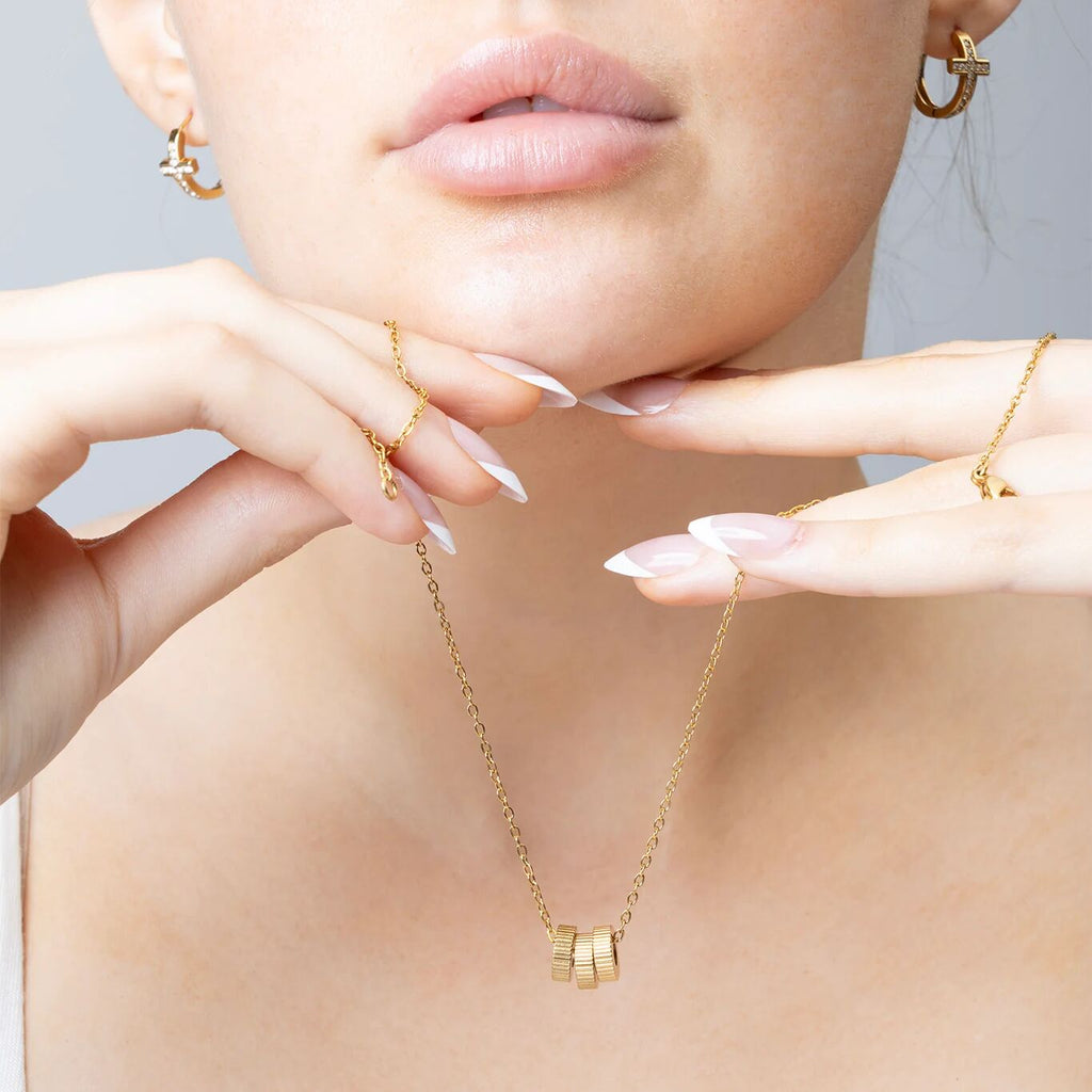 Gold necklace worn by a person with a neutral background