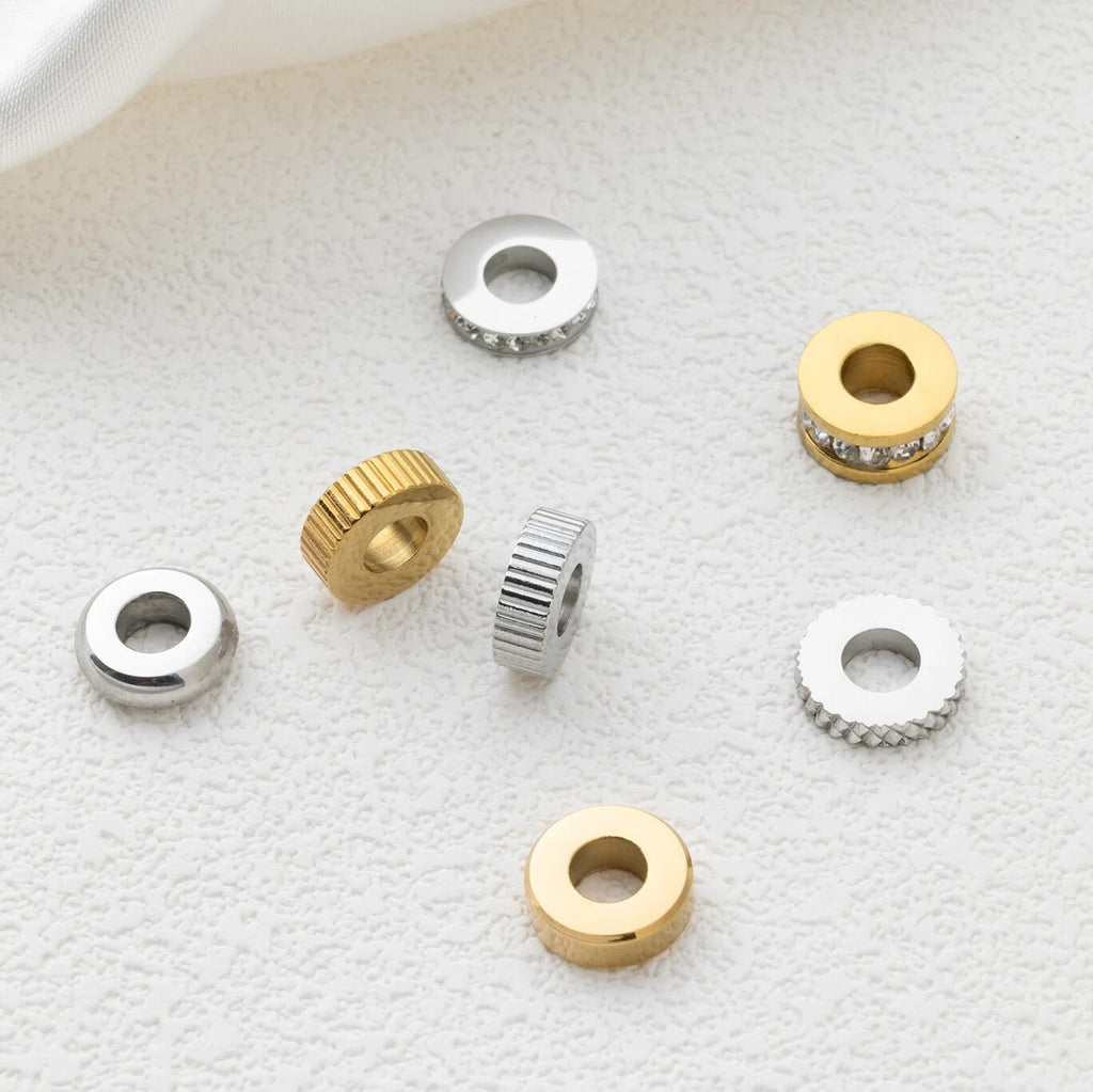 Gold and silver spacer beads on a textured white surface