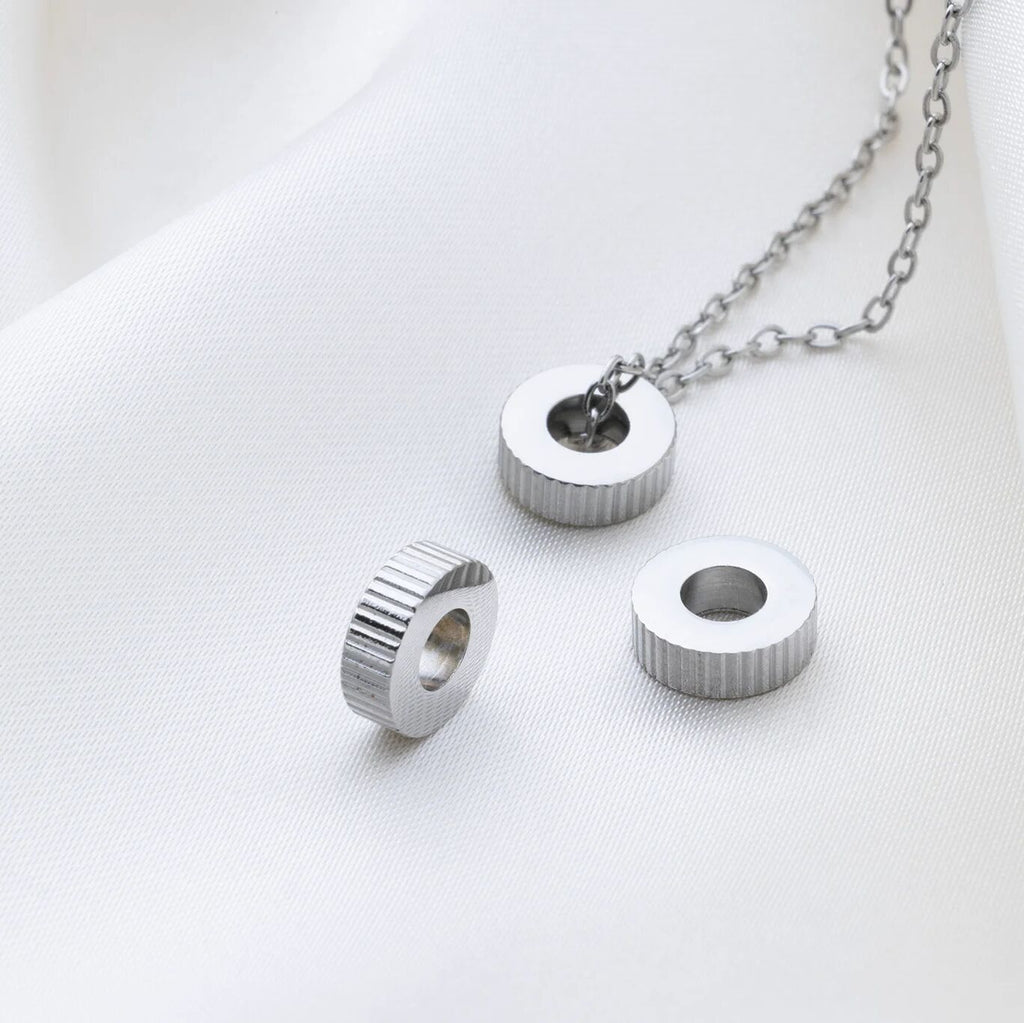 Silver necklace with fluted spacer beads on a white background