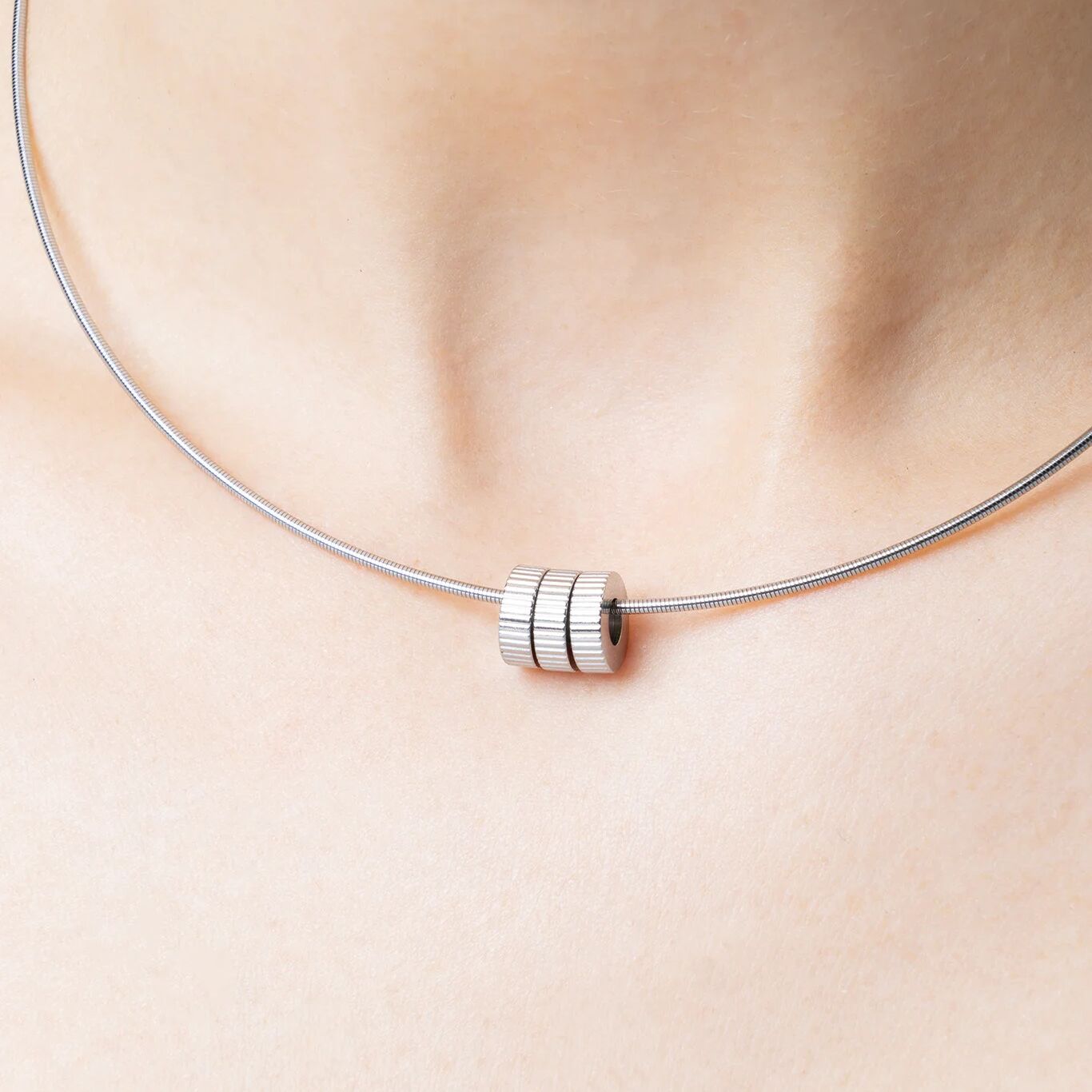 Silver necklace with fluted spacer beads against a person's neck