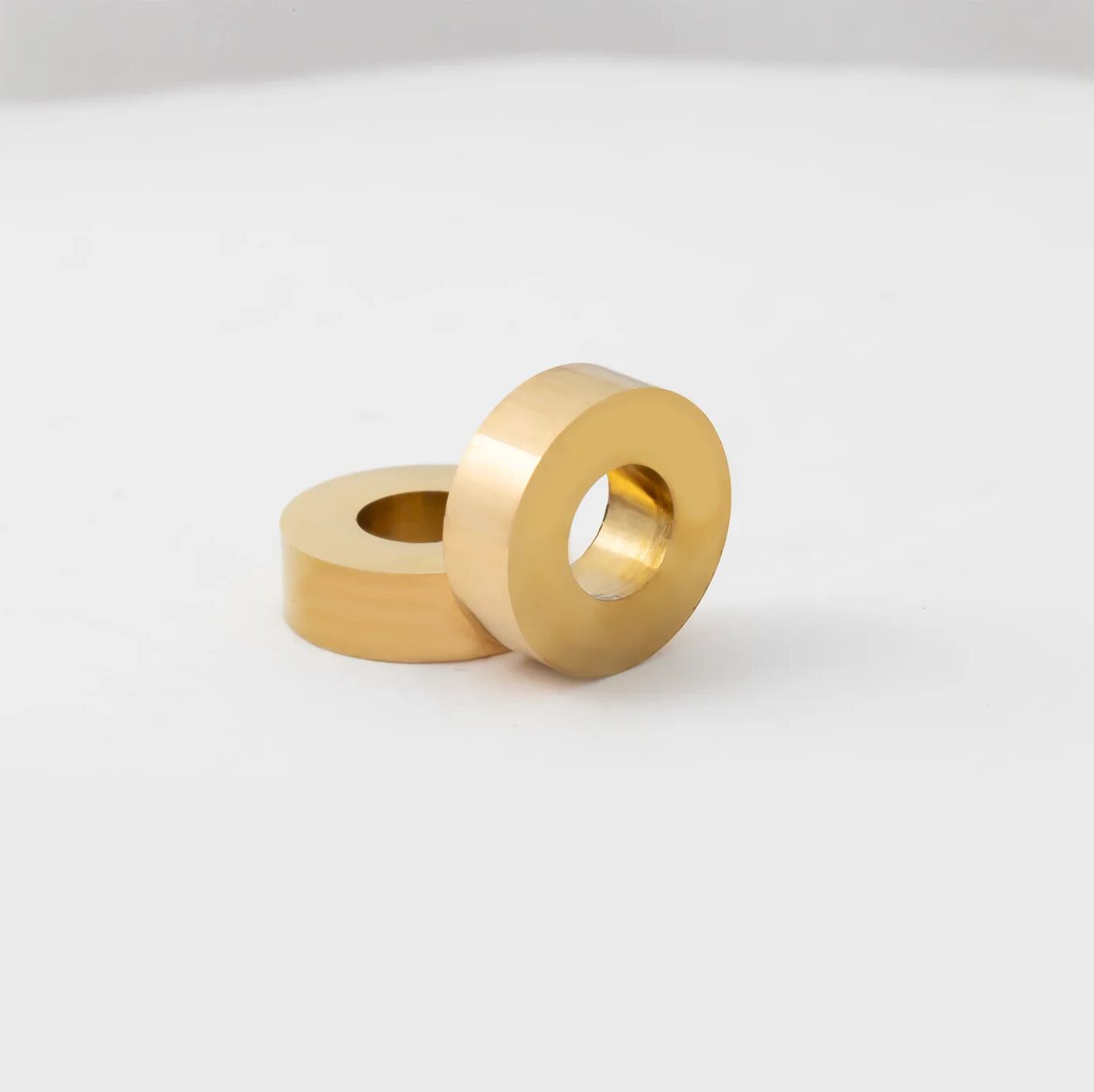 Two gold spacer beads on a white background
