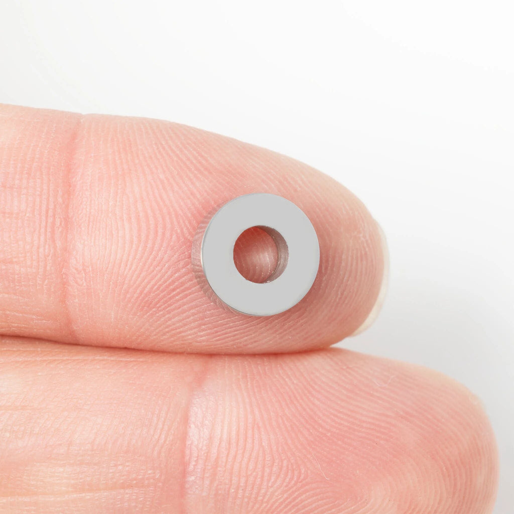 Small spacer bead held between fingers against a white background