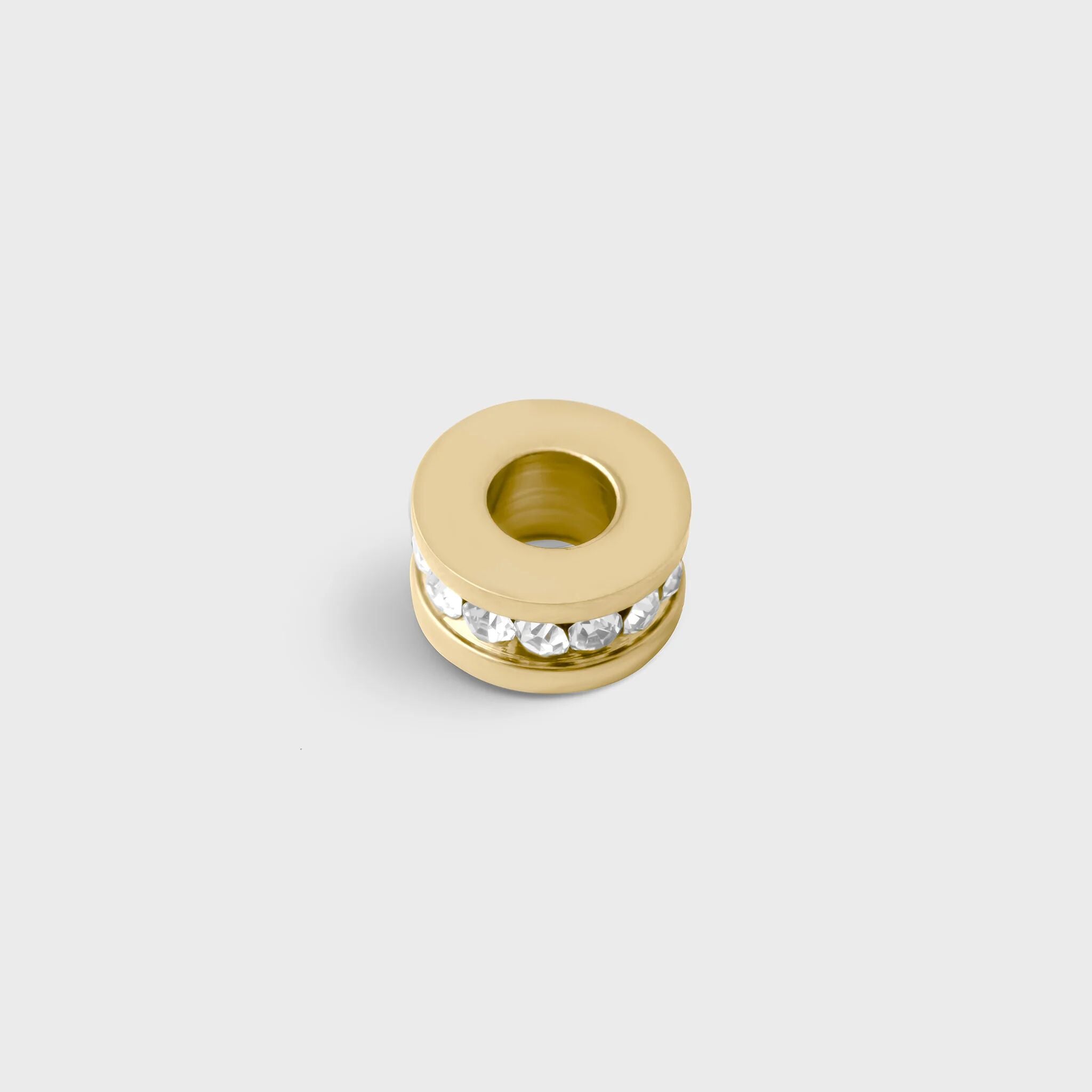 Gold spacer bead with embedded stones on a light gray background