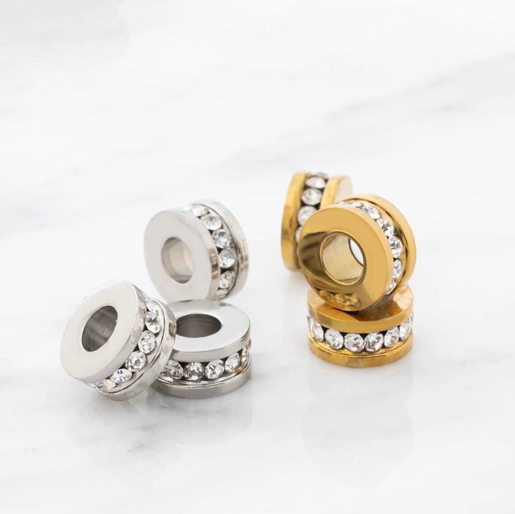 Silver and gold spacer beads with clear stones on a white background