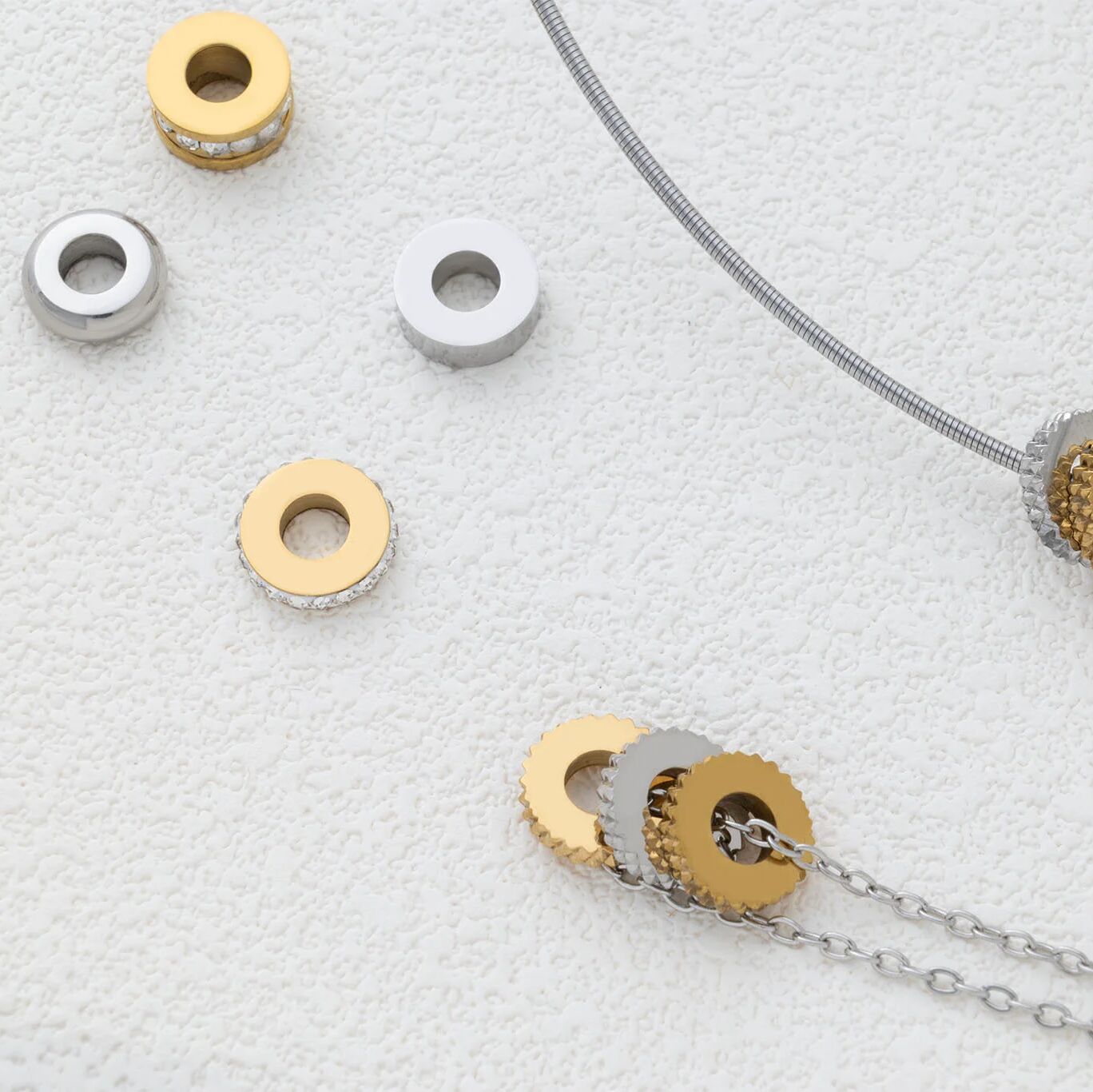 Gold and silver textured spacer beads on a textured white surface