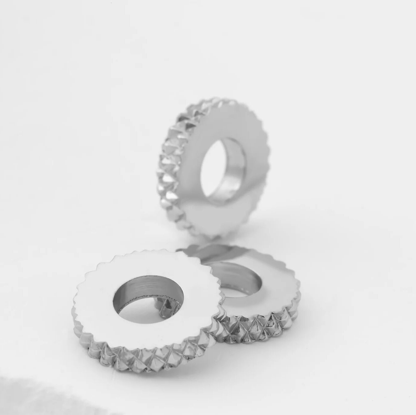 Two silver textured spacer beads on a light gray background