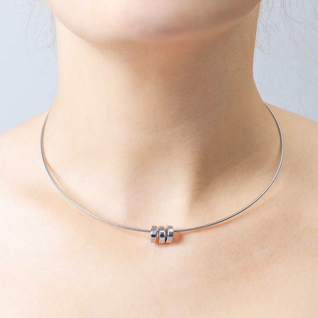 Silver necklace with spacer bead on a neck against a light background