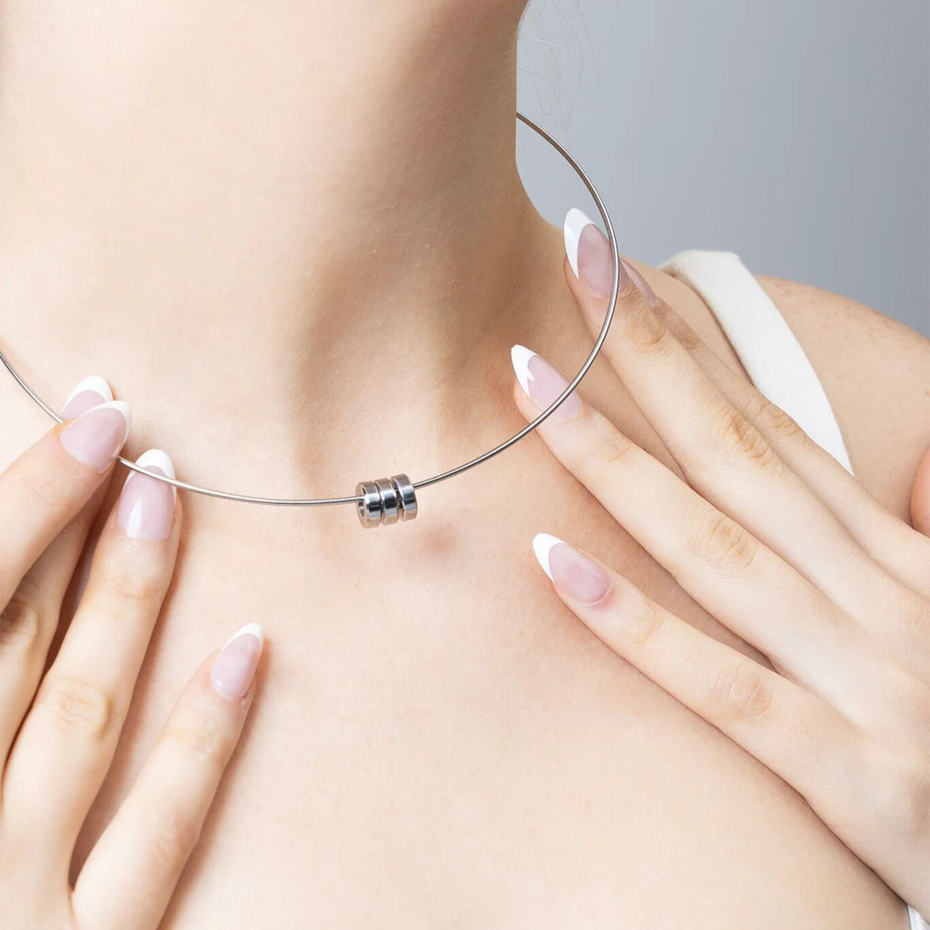 Close-up of a necklace being worn with hands adjusting it on a neutral background