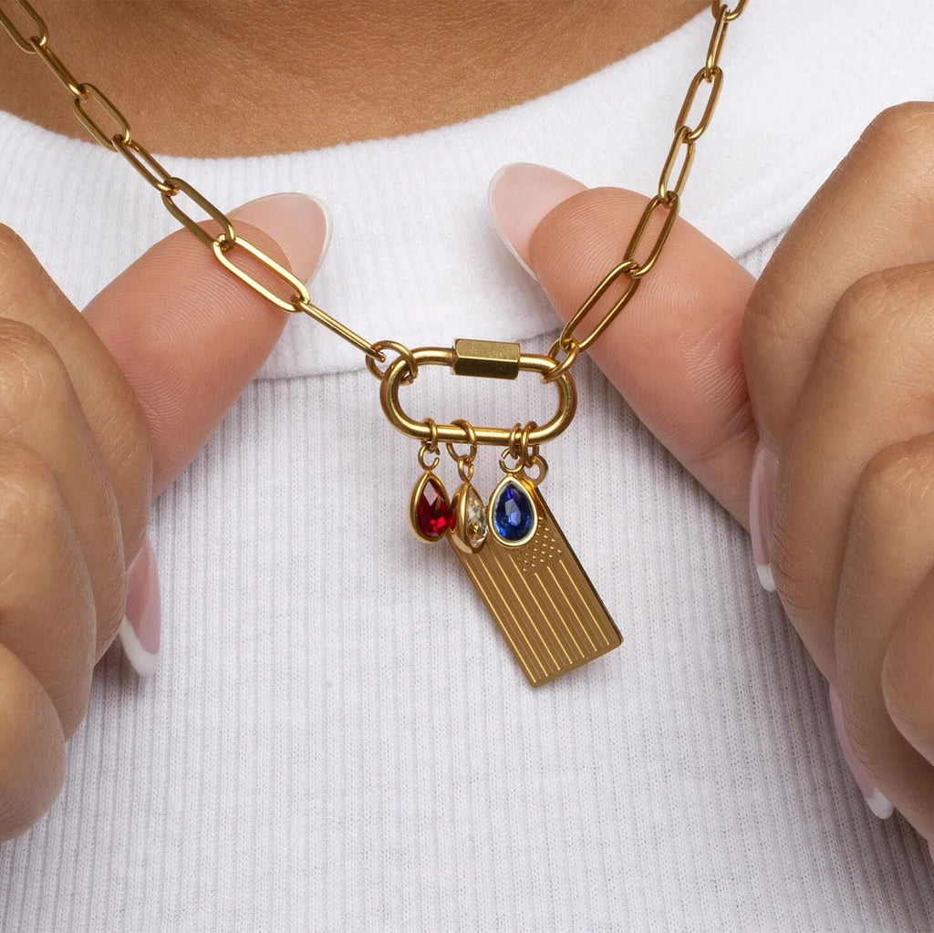 Gold necklace with charms held by hands against a white background