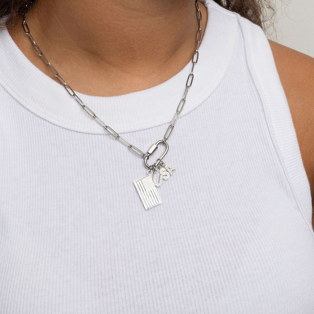 Silver chain necklace with charms worn by a person in a white tank top.