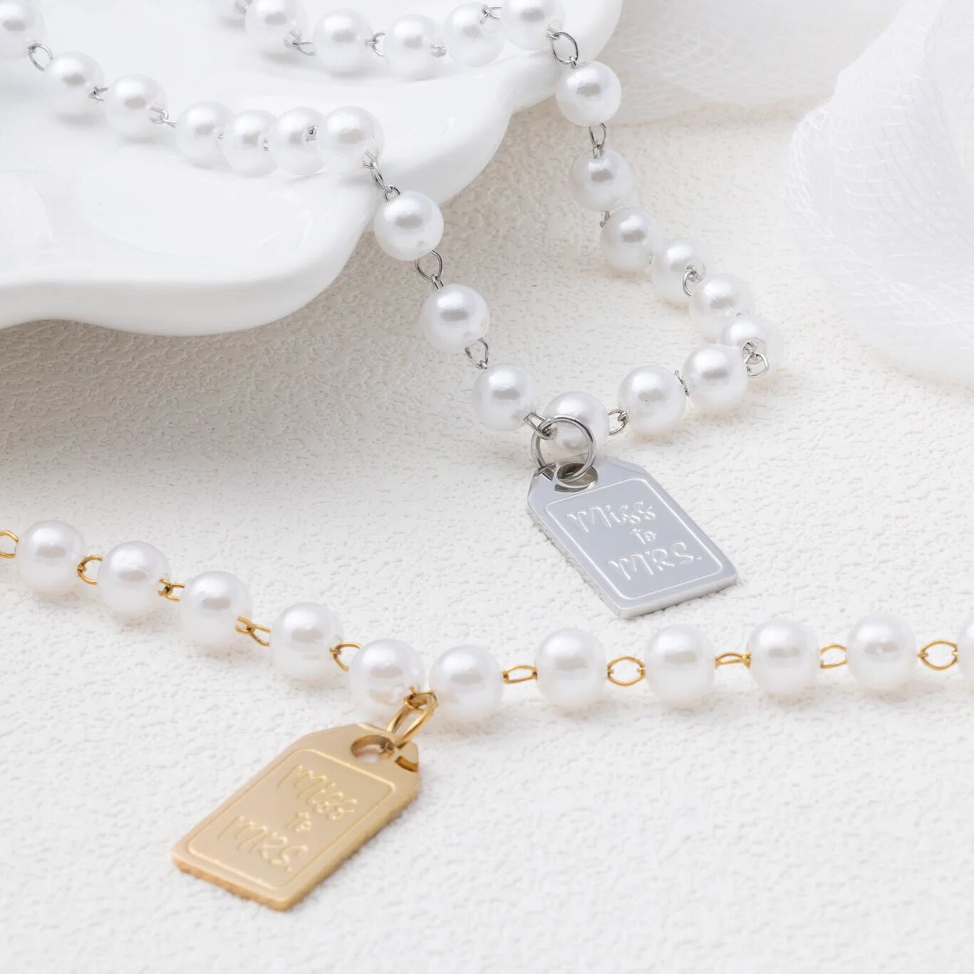 Pearl necklace with engraved tags on a light background