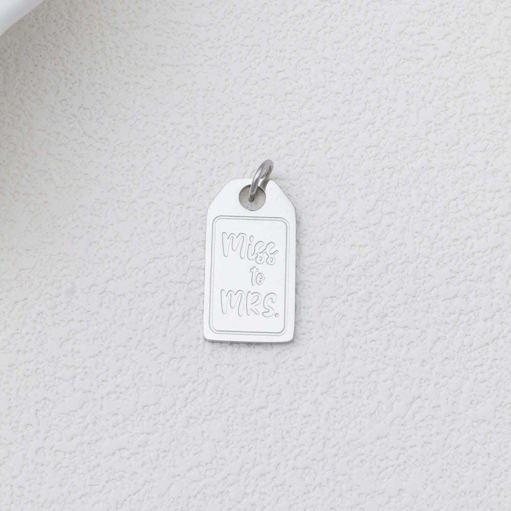 Silver 'Miss to Mrs.' charm on a textured white background