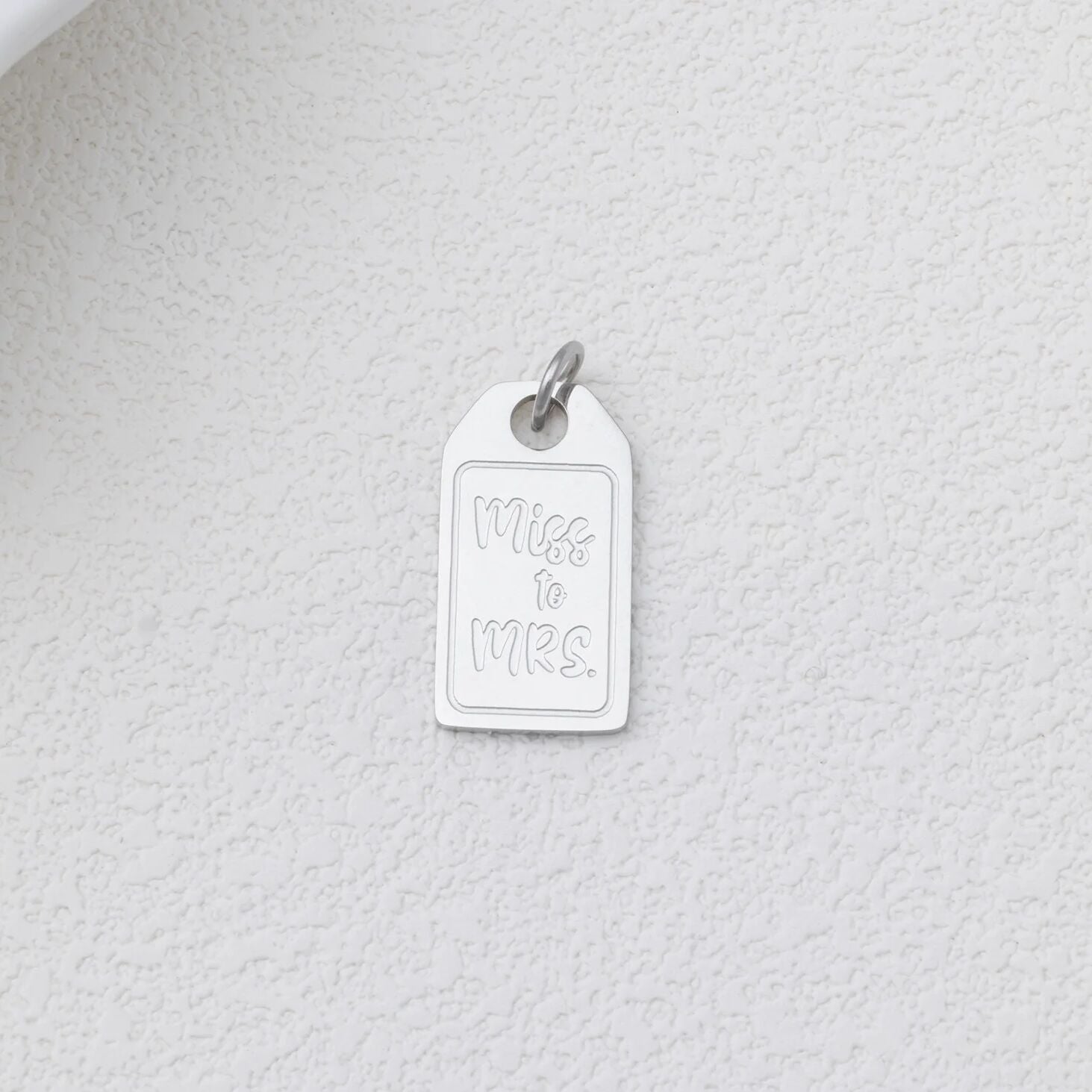 Silver 'Miss to Mrs.' charm on a textured white background