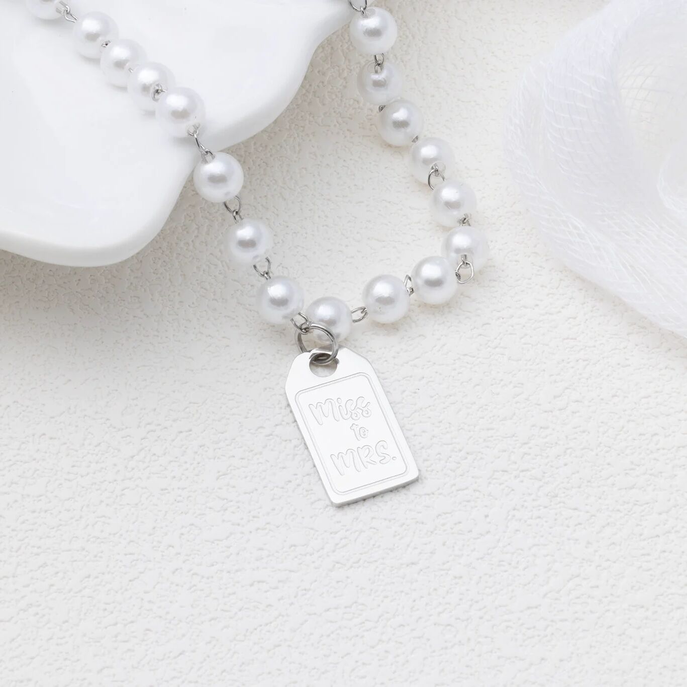 Pearl necklace with a silver tag on a white background