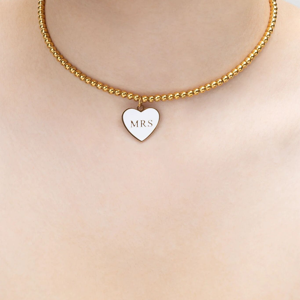 Gold necklace with a heart-shaped 'MRS' pendant on a plain background