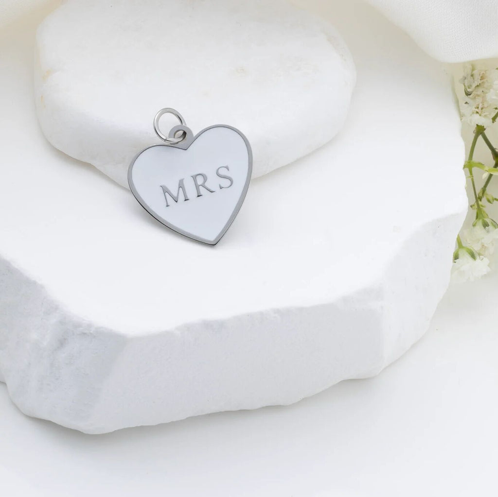 Silver heart-shaped pendant with 'MRS' engraving on a white background